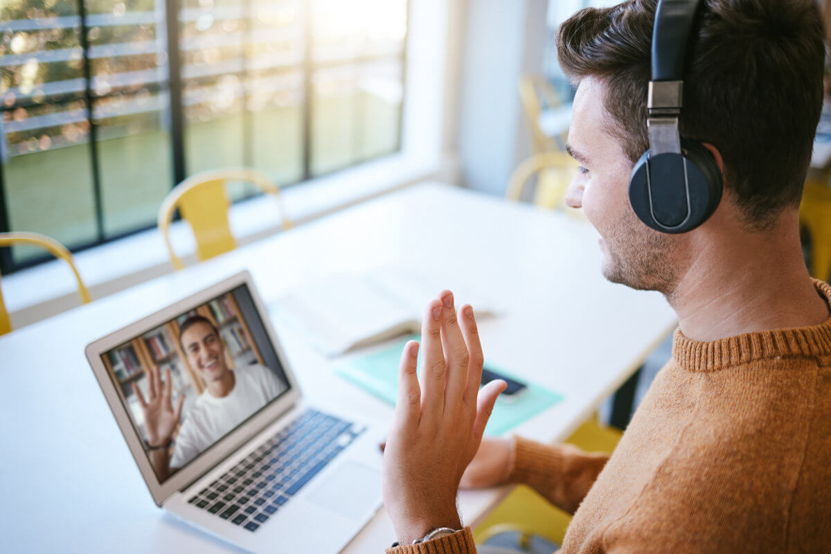 Video call on laptop with 2 participants waving hello to each other