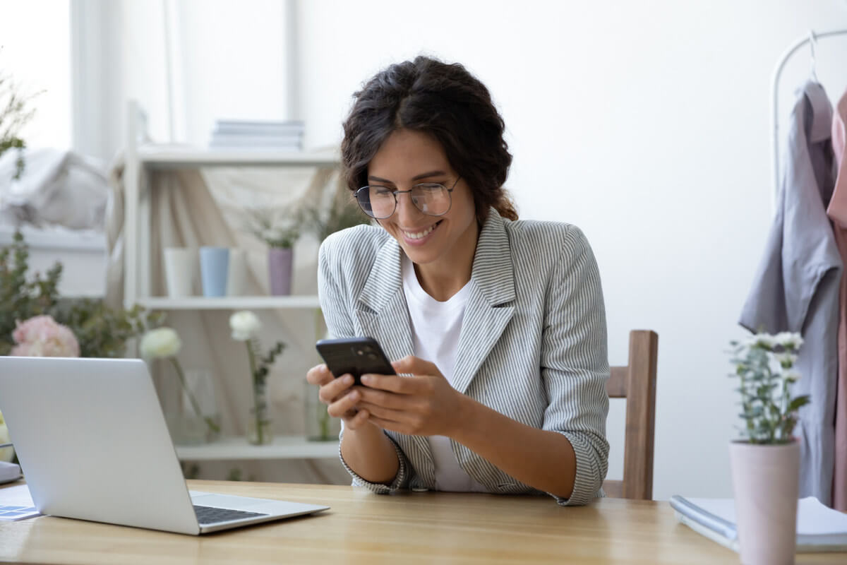 Good news excited young female self employed clothing designer sitting at work desk